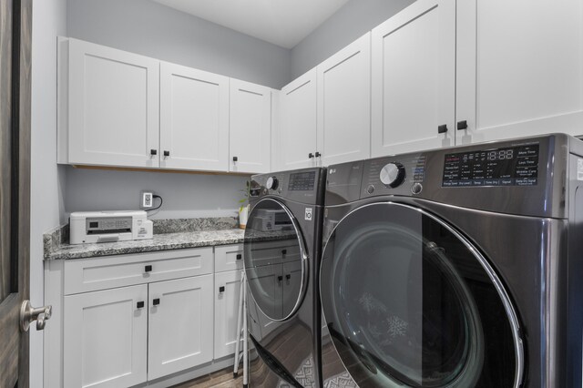 clothes washing area featuring cabinet space and washing machine and dryer