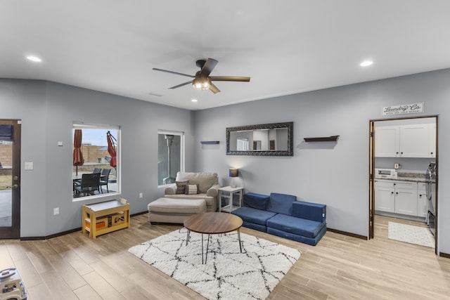 living area with baseboards, light wood-type flooring, a ceiling fan, and recessed lighting