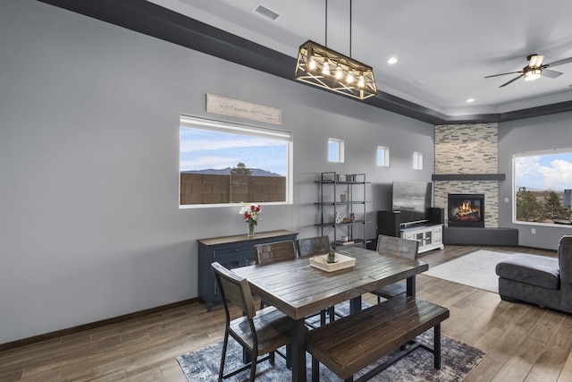 dining area featuring a wealth of natural light, visible vents, wood finished floors, and a stone fireplace