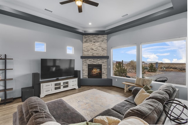 living area with light wood-style flooring, a fireplace, visible vents, and baseboards