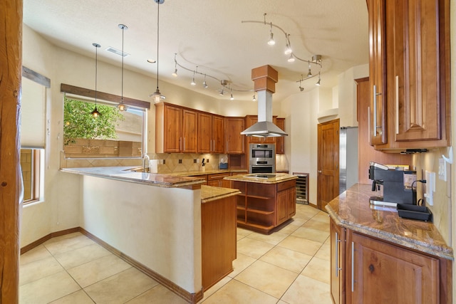 kitchen with double oven, beverage cooler, a center island, light stone counters, and kitchen peninsula