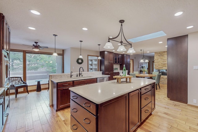 kitchen with a center island, decorative light fixtures, a skylight, and sink