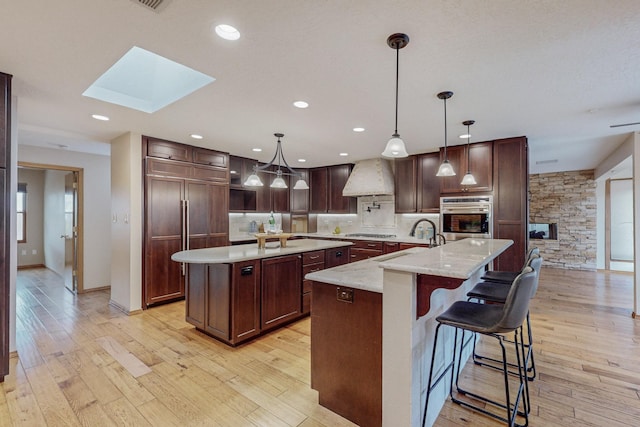 kitchen with oven, a spacious island, sink, and a skylight