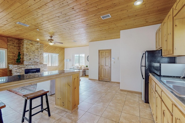 kitchen with ceiling fan, wooden ceiling, a breakfast bar area, and light brown cabinetry