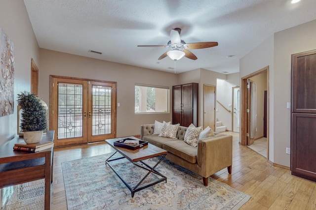 living room featuring a wealth of natural light, french doors, a textured ceiling, and light wood-type flooring