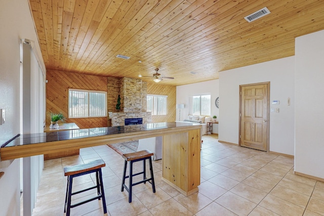 kitchen featuring a breakfast bar area, kitchen peninsula, wood walls, and wood ceiling