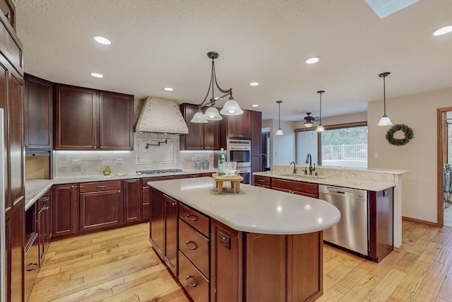 kitchen with a kitchen island, sink, premium range hood, and appliances with stainless steel finishes