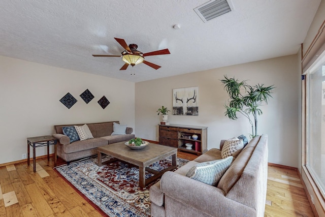 living room with ceiling fan, light hardwood / wood-style floors, and a textured ceiling