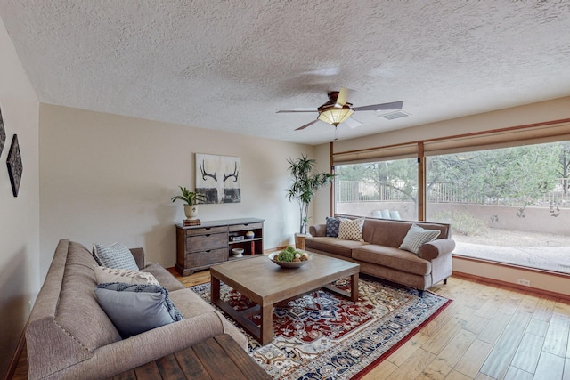 living room featuring a textured ceiling, light hardwood / wood-style flooring, a wealth of natural light, and ceiling fan