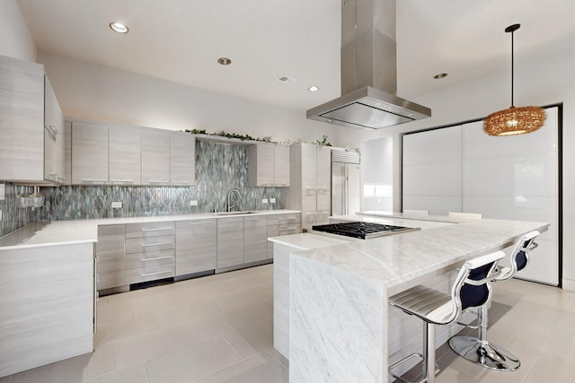 kitchen featuring a center island, tasteful backsplash, pendant lighting, island range hood, and light tile patterned floors