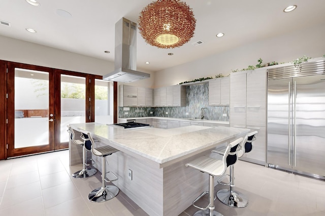 kitchen with a kitchen island, island exhaust hood, appliances with stainless steel finishes, and a breakfast bar area