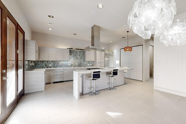 kitchen featuring a large island, sink, tasteful backsplash, island exhaust hood, and a breakfast bar