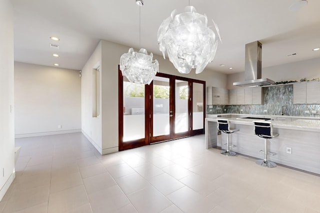 kitchen with a breakfast bar, french doors, sink, decorative backsplash, and island exhaust hood