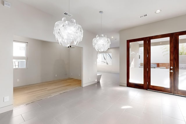 interior space with french doors, light tile patterned floors, an inviting chandelier, and a wealth of natural light