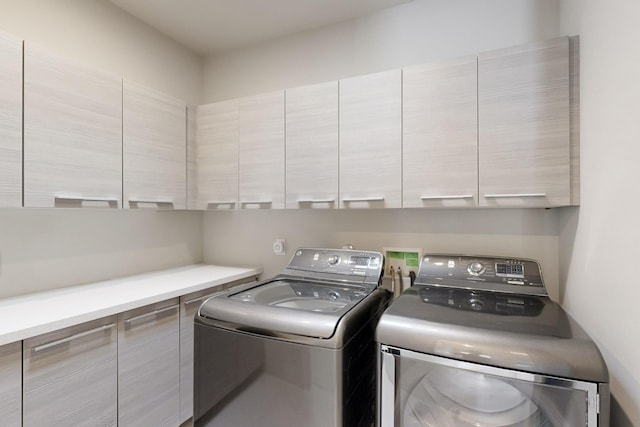 clothes washing area featuring cabinets and separate washer and dryer