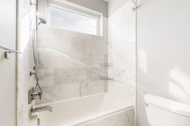 bathroom featuring toilet and tiled shower / bath