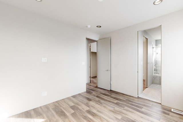 unfurnished bedroom featuring ensuite bath and light hardwood / wood-style flooring