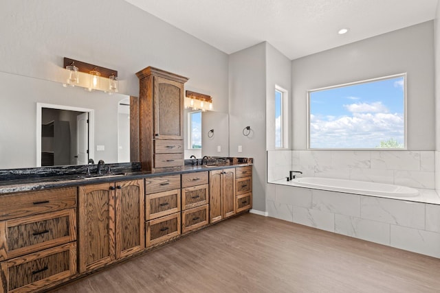 bathroom with vanity, hardwood / wood-style flooring, and a relaxing tiled tub