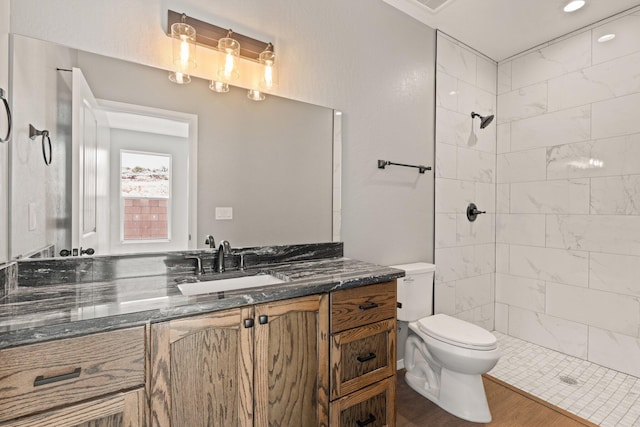 bathroom featuring a tile shower, vanity, hardwood / wood-style flooring, and toilet