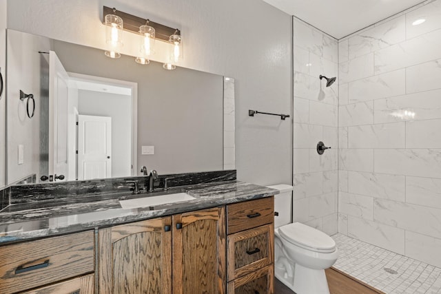 bathroom featuring tiled shower, hardwood / wood-style flooring, vanity, and toilet