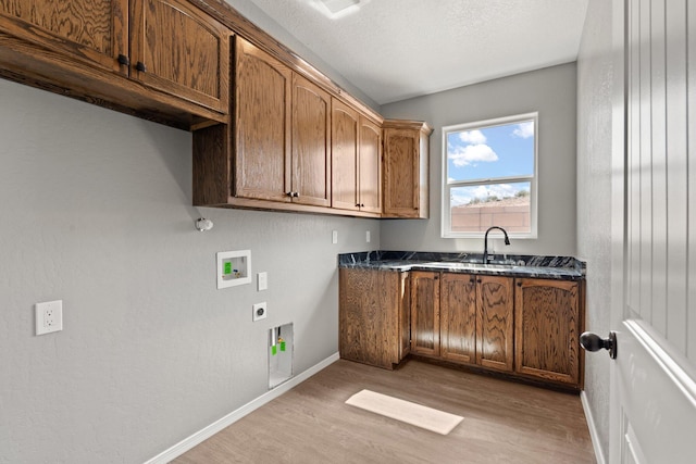 laundry area with sink, cabinets, hookup for an electric dryer, hookup for a washing machine, and light wood-type flooring