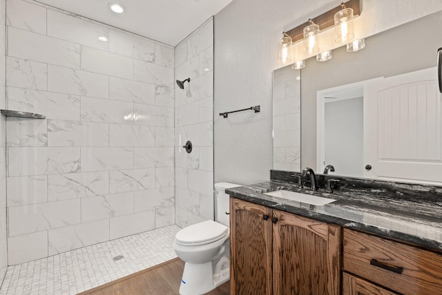 bathroom featuring tiled shower, hardwood / wood-style floors, vanity, and toilet