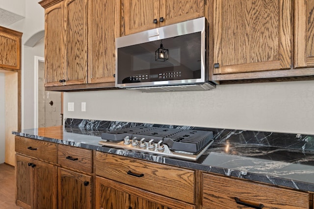 kitchen with hardwood / wood-style flooring, dark stone counters, and gas cooktop