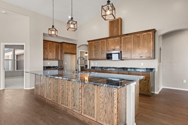 kitchen with pendant lighting, high vaulted ceiling, sink, a large island, and stainless steel appliances