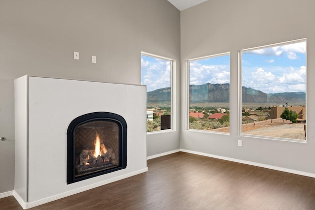 unfurnished living room featuring a mountain view, dark hardwood / wood-style floors, and a healthy amount of sunlight