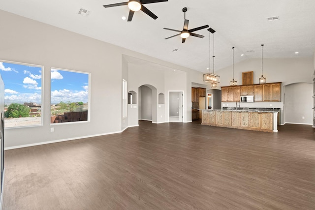 unfurnished living room featuring dark hardwood / wood-style floors, high vaulted ceiling, ceiling fan, and sink