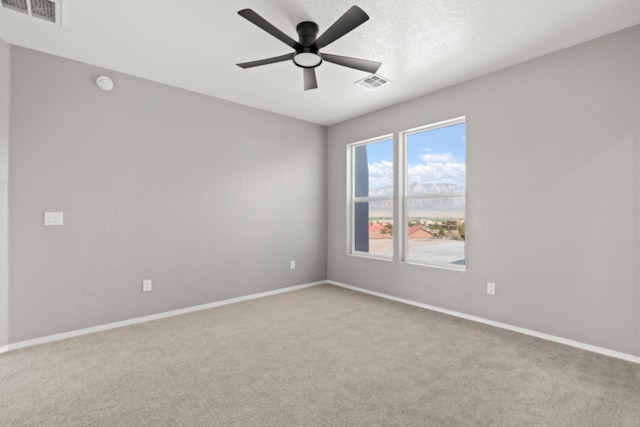 empty room with ceiling fan, light colored carpet, and a textured ceiling