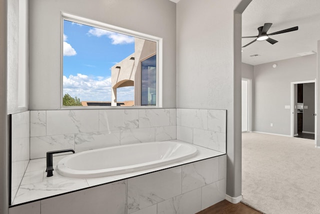 bathroom featuring ceiling fan and tiled tub