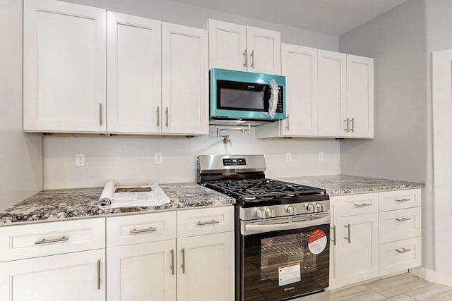 kitchen with light stone counters, stainless steel range with gas stovetop, and white cabinets