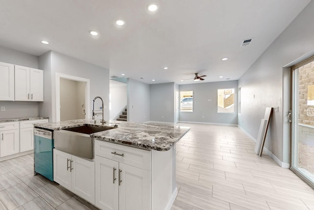 kitchen featuring sink, white cabinets, a kitchen island with sink, stainless steel dishwasher, and light stone counters