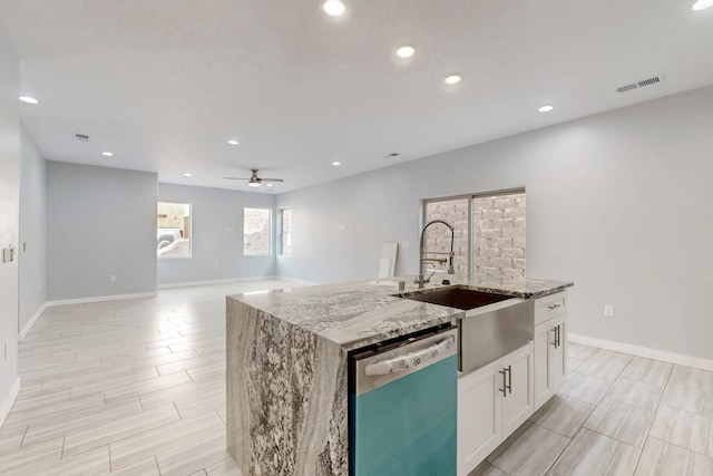 kitchen with sink, light stone counters, a center island with sink, dishwasher, and white cabinets