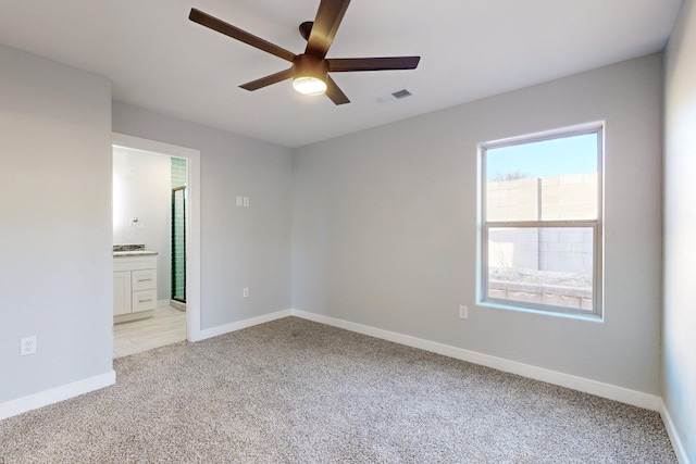 unfurnished bedroom with light carpet, ceiling fan, and ensuite bathroom