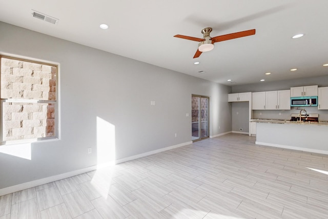 unfurnished living room featuring ceiling fan and sink