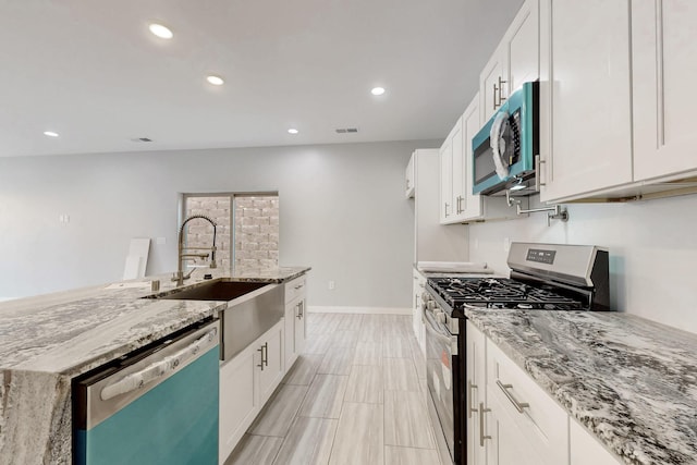 kitchen with white cabinetry, appliances with stainless steel finishes, sink, and light stone counters