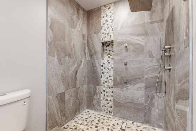 bathroom with a tile shower and toilet