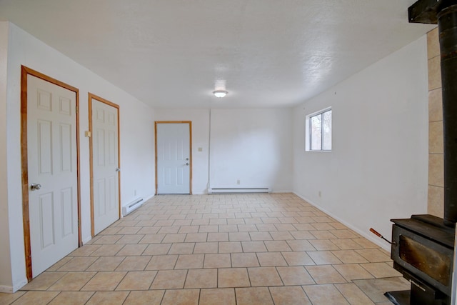 spare room featuring a wood stove and a baseboard radiator