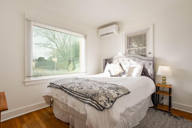 bedroom with dark hardwood / wood-style floors and an AC wall unit