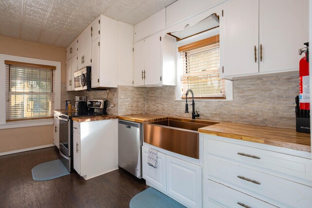 kitchen with stainless steel appliances, white cabinetry, sink, and backsplash