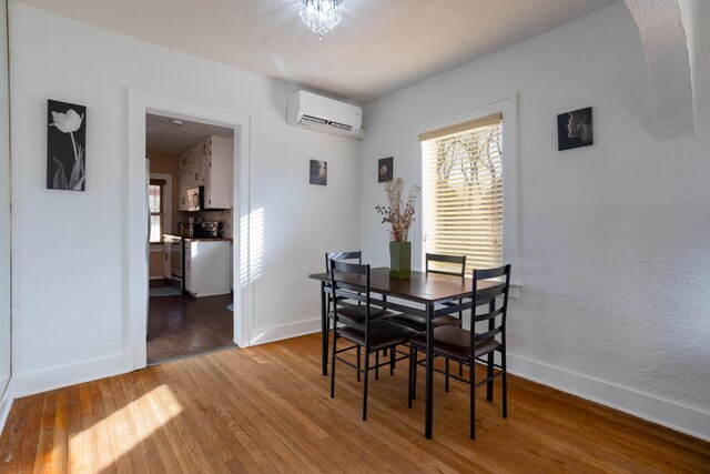 dining area with hardwood / wood-style floors and a wall unit AC