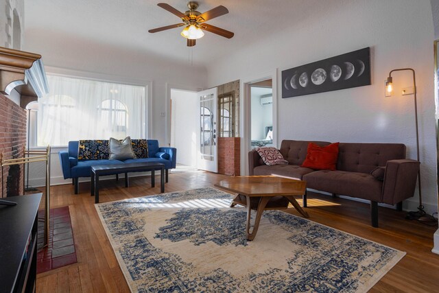 living room featuring dark wood-type flooring, ceiling fan, and a wall mounted AC