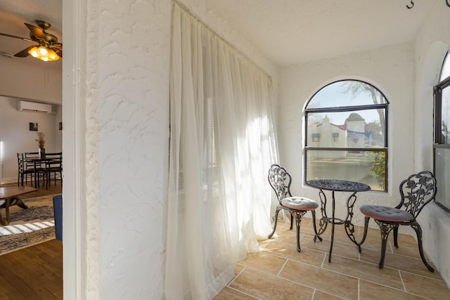 living area with ceiling fan and a wall unit AC