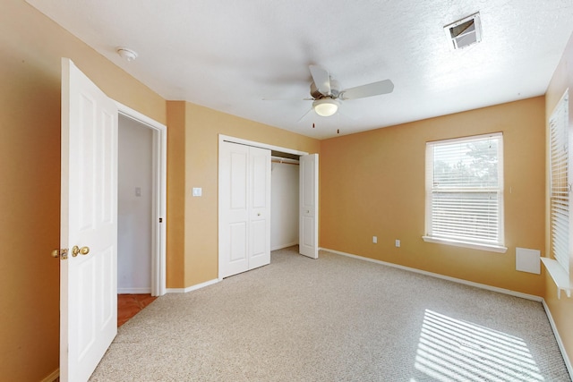 unfurnished bedroom featuring ceiling fan, a closet, and light carpet