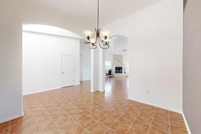 unfurnished dining area featuring light tile patterned floors, ceiling fan with notable chandelier, and vaulted ceiling