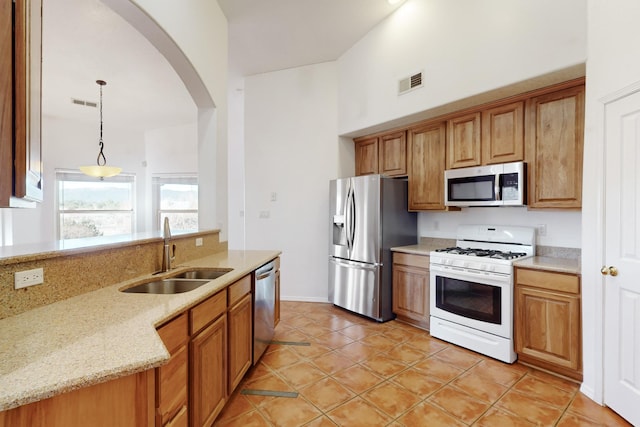 kitchen with sink, hanging light fixtures, light stone countertops, light tile patterned flooring, and stainless steel appliances