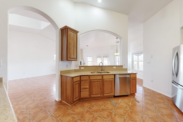 kitchen with sink, light tile patterned floors, hanging light fixtures, and appliances with stainless steel finishes