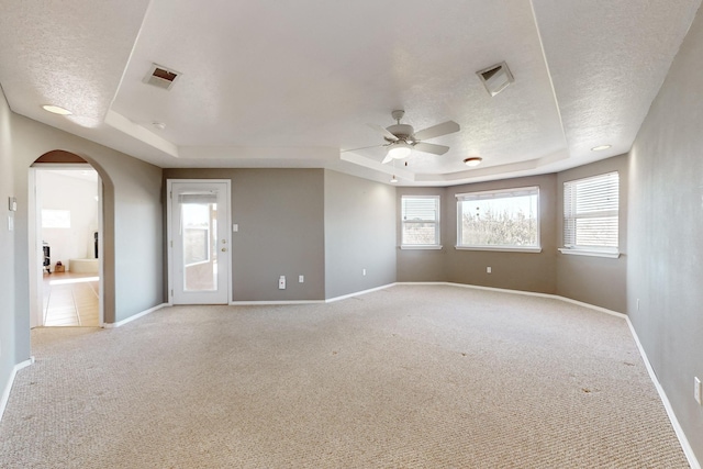 carpeted empty room with ceiling fan, a textured ceiling, and a tray ceiling